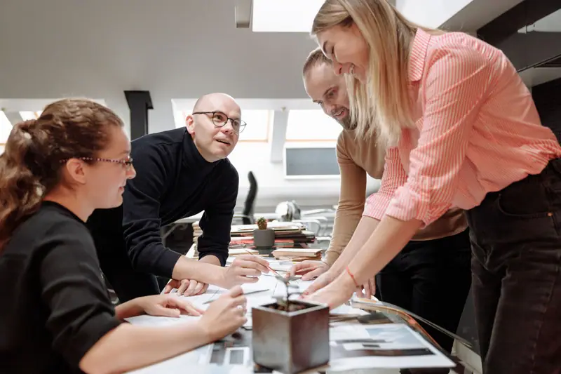 Kolleger som diskuterer et prosjekt rundt et bord på et moderne kontor